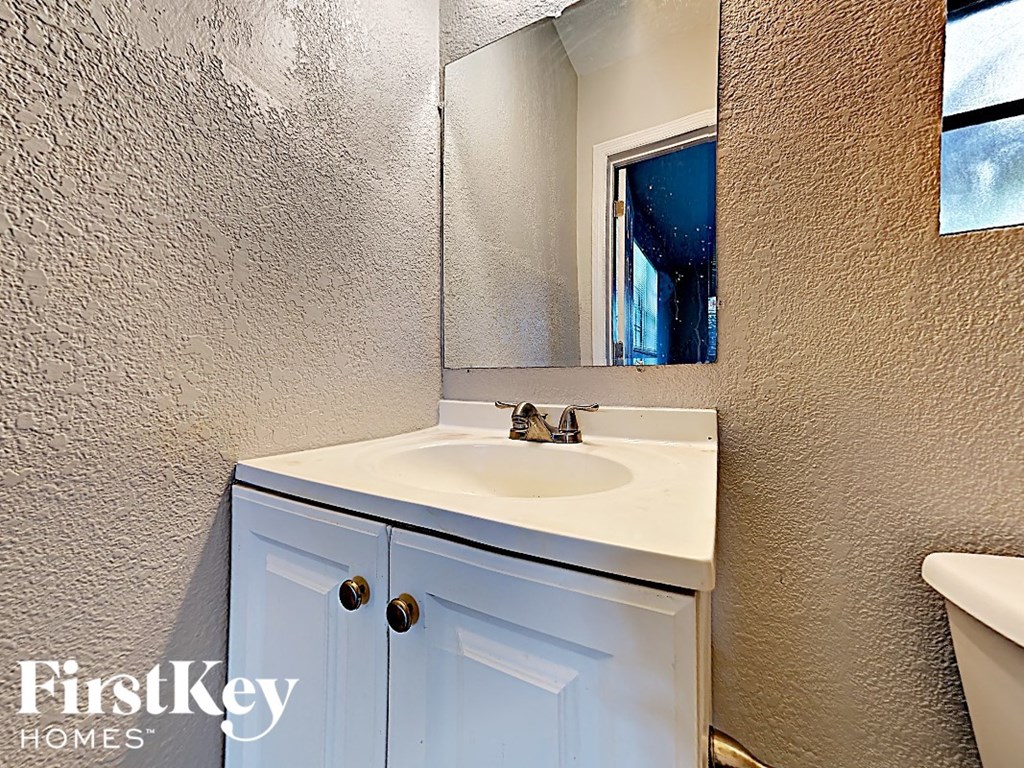 A bathroom with a white sink and a mirror.