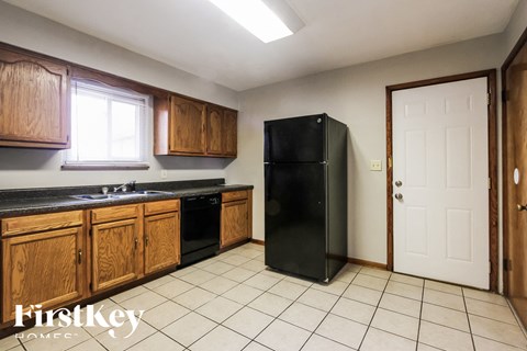 A kitchen with wooden cabinets and a black fridge.