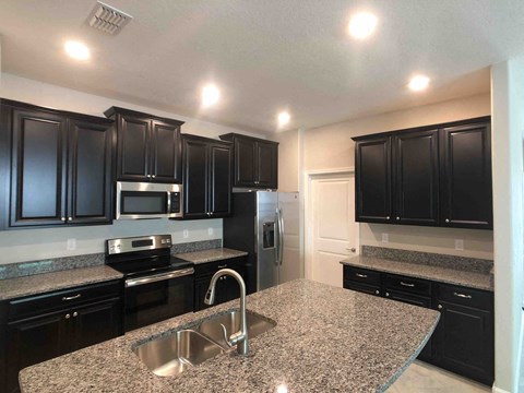 A kitchen with black cabinets and granite countertops.