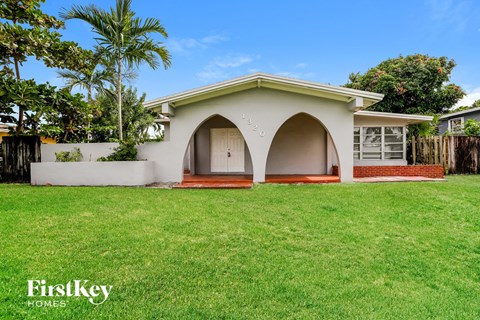 a small white house with an arched porch and a green lawn
