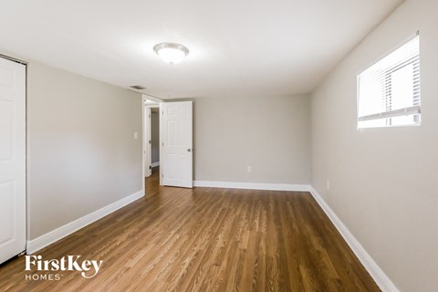 the living room of an apartment with wood flooring and white walls
