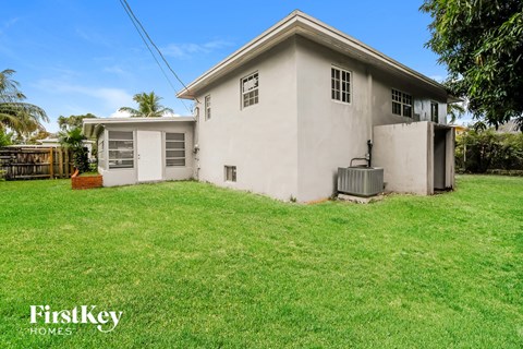 a small white house with a grass yard and a garage