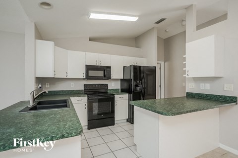 a white kitchen with black appliances and green counter tops