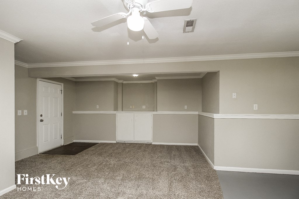 A spacious room with a carpeted floor and a ceiling fan.