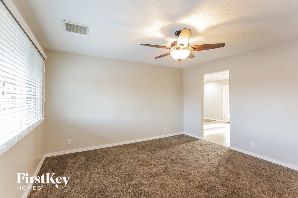 A room with a ceiling fan and carpeted floor.