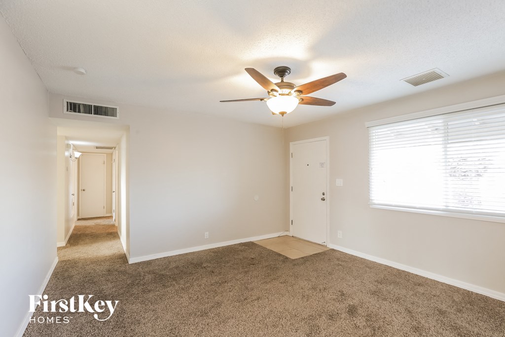 A spacious room with a carpeted floor and a ceiling fan.