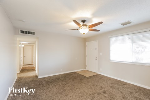 A spacious room with a carpeted floor and a ceiling fan.