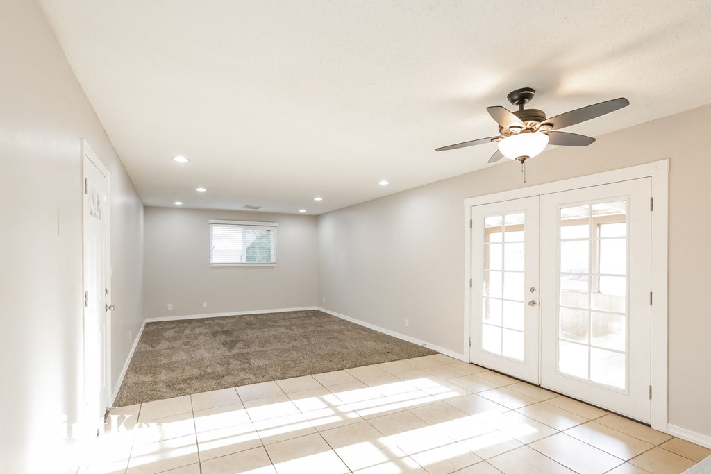 A sunny room with a fan and a rug on the floor.