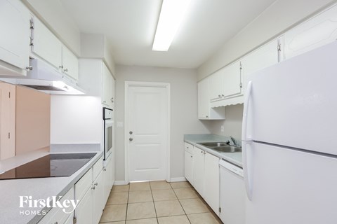 A kitchen with white cabinets and a white refrigerator.
