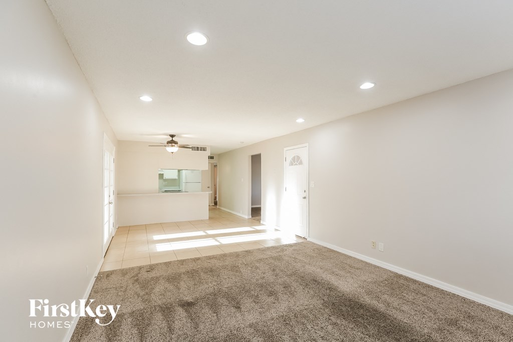 A spacious room with a carpeted floor and a ceiling fan.