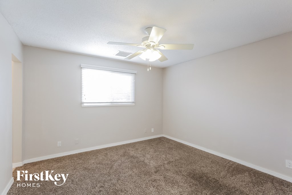 A room with a ceiling fan and a window.