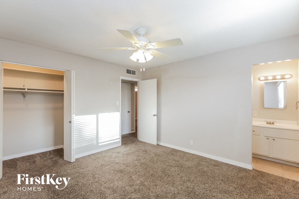 A spacious bedroom with a carpeted floor and a ceiling fan.