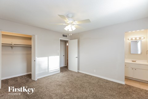 A spacious bedroom with a carpeted floor and a ceiling fan.