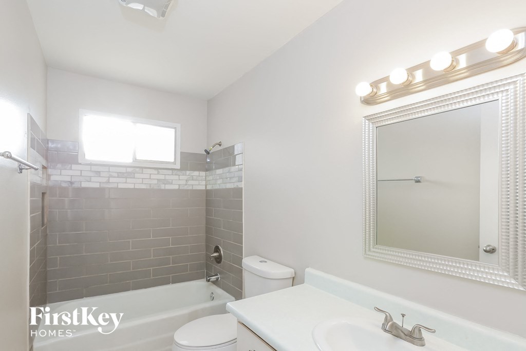 A white bathroom with a mirror and a toilet.