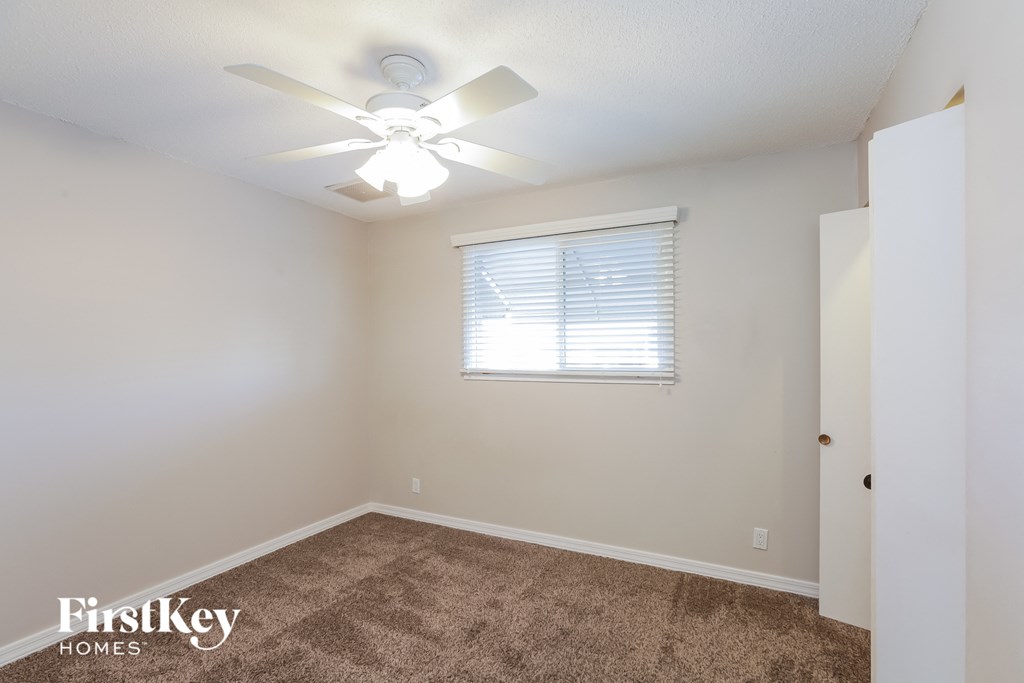 A room with a carpet floor and a ceiling fan.