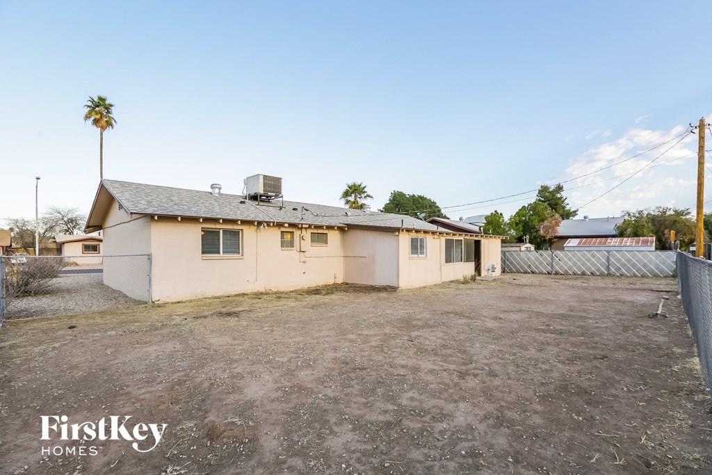 A house with a fence and a palm tree in the background.