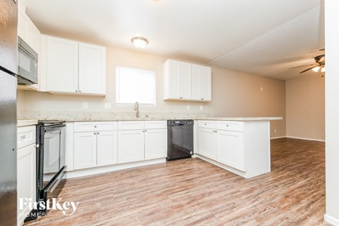 A kitchen with white cabinets and a wooden floor.