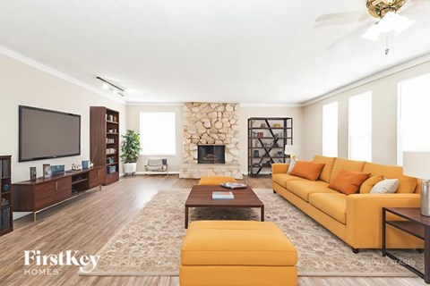 A living room with a yellow couch and a fireplace.