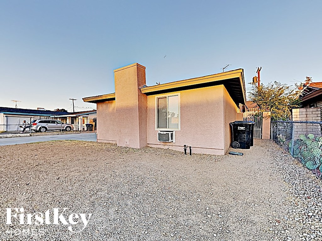 A house with a brown roof and a gravel driveway in front of it.