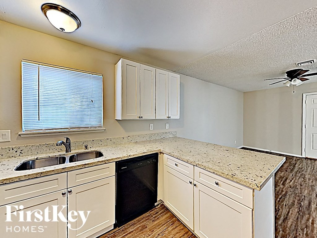 A kitchen with a sink, cabinets and a window.
