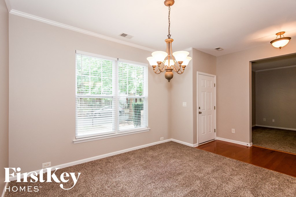 an empty dining room with a large window and a chandelier