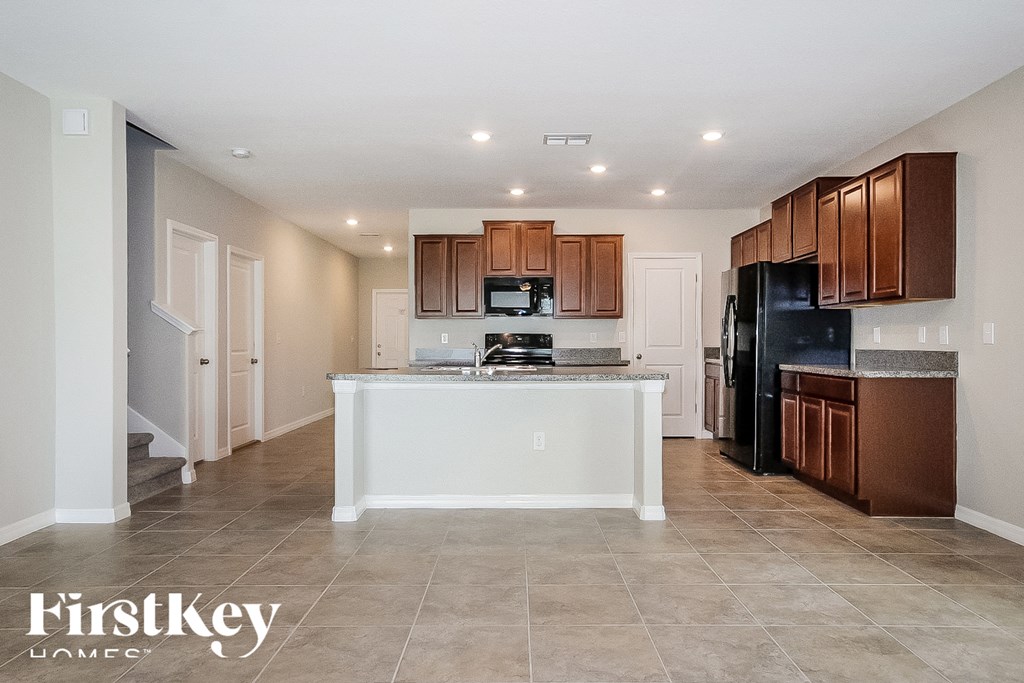 a kitchen with a large island and a black refrigerator