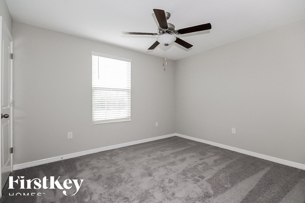 a bedroom with gray carpet and a ceiling fan