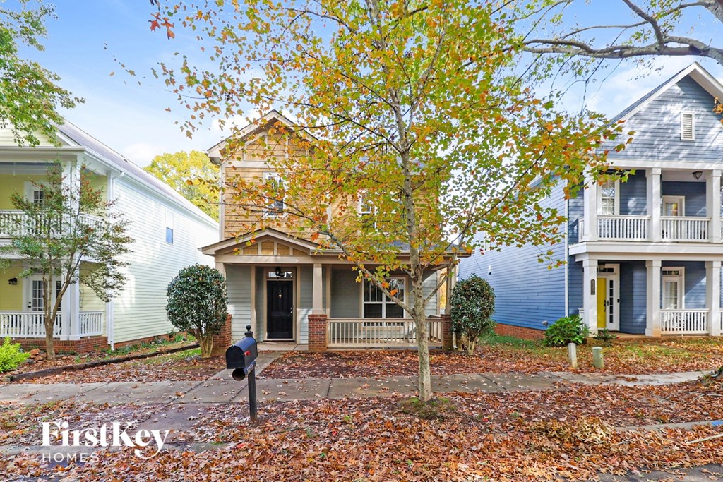 A house with a blue roof and a tree with yellow leaves in front of it.