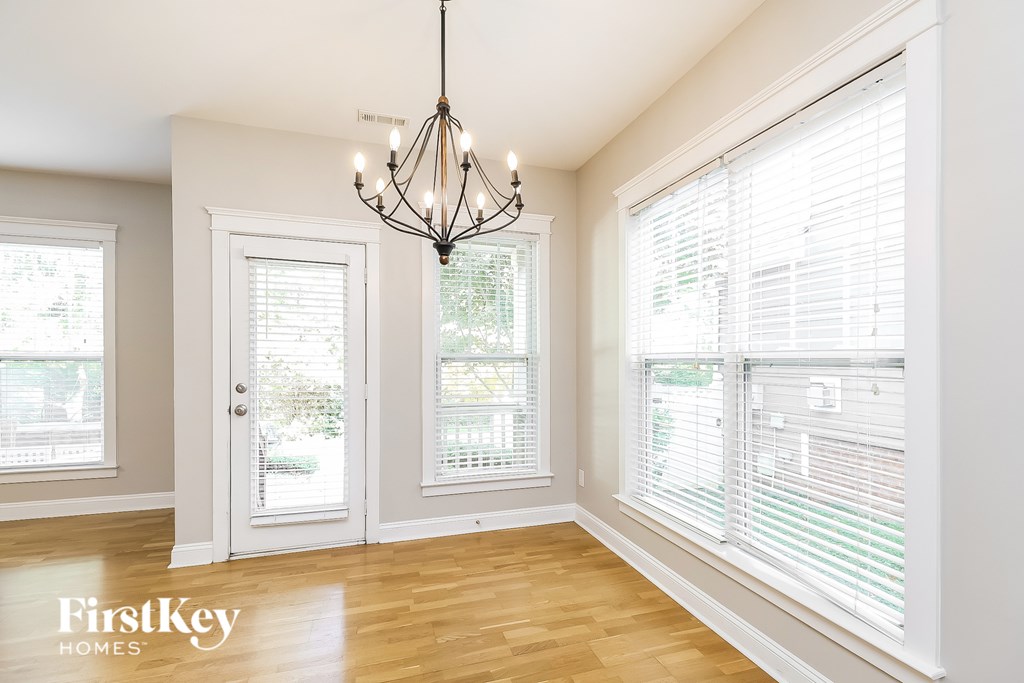 A well lit room with a chandelier and a window with blinds.