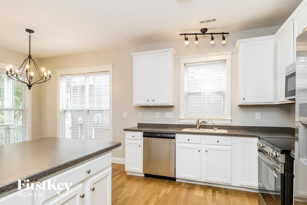 A kitchen with white cabinets and a black countertop.