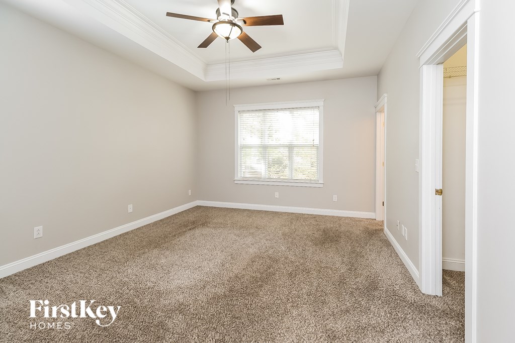 A room with a carpeted floor and a ceiling fan.
