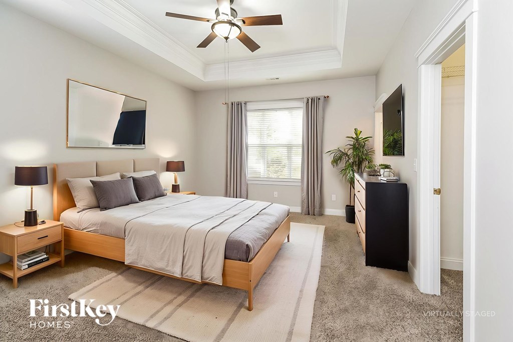 A bedroom with a large bed, a ceiling fan, and a rug on the floor.