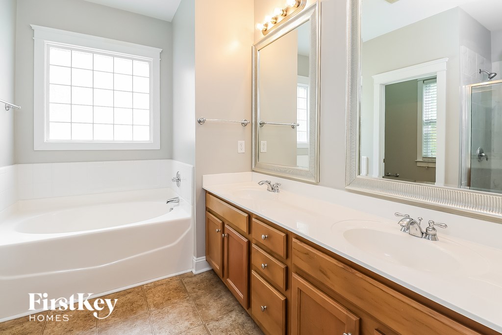 A bathroom with a tub, sink, and mirror.