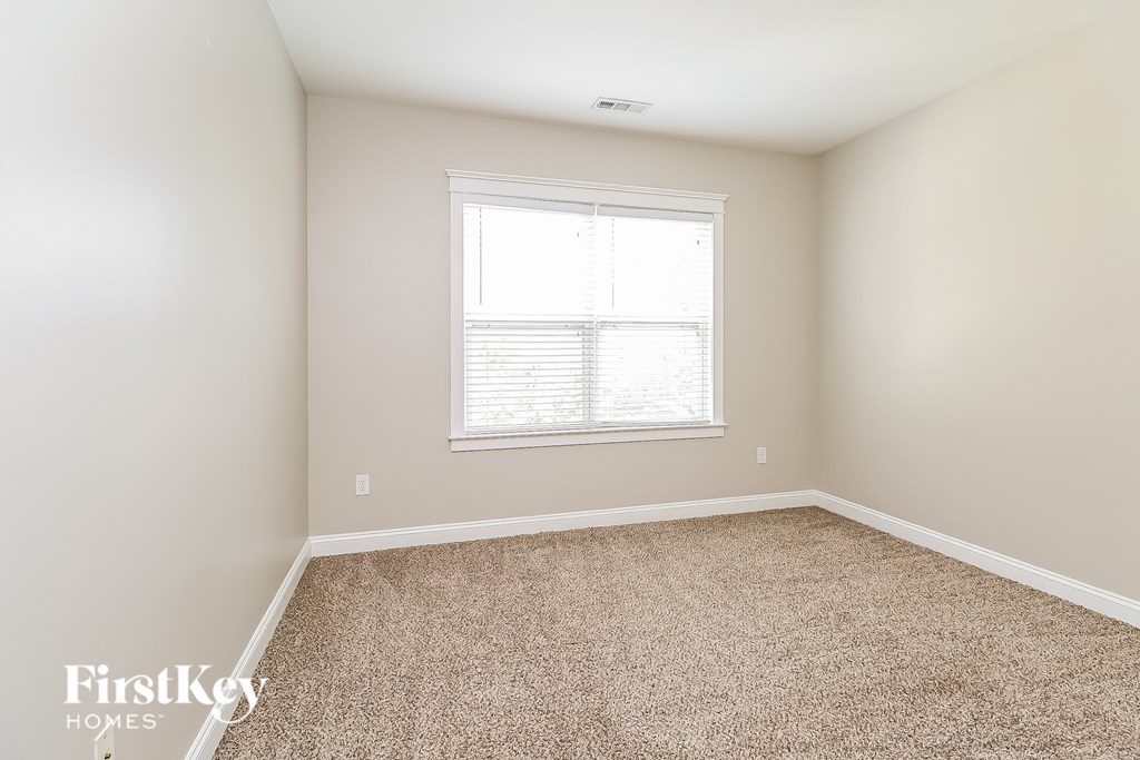 A room with a carpeted floor and a window with blinds.