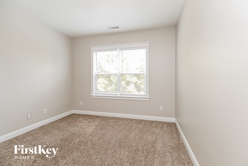 A room with a carpeted floor and a window letting in light.