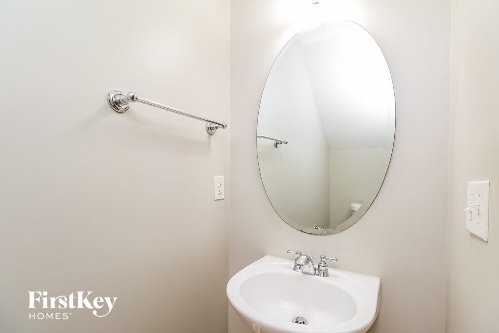 A bathroom with a sink, mirror and a shower.