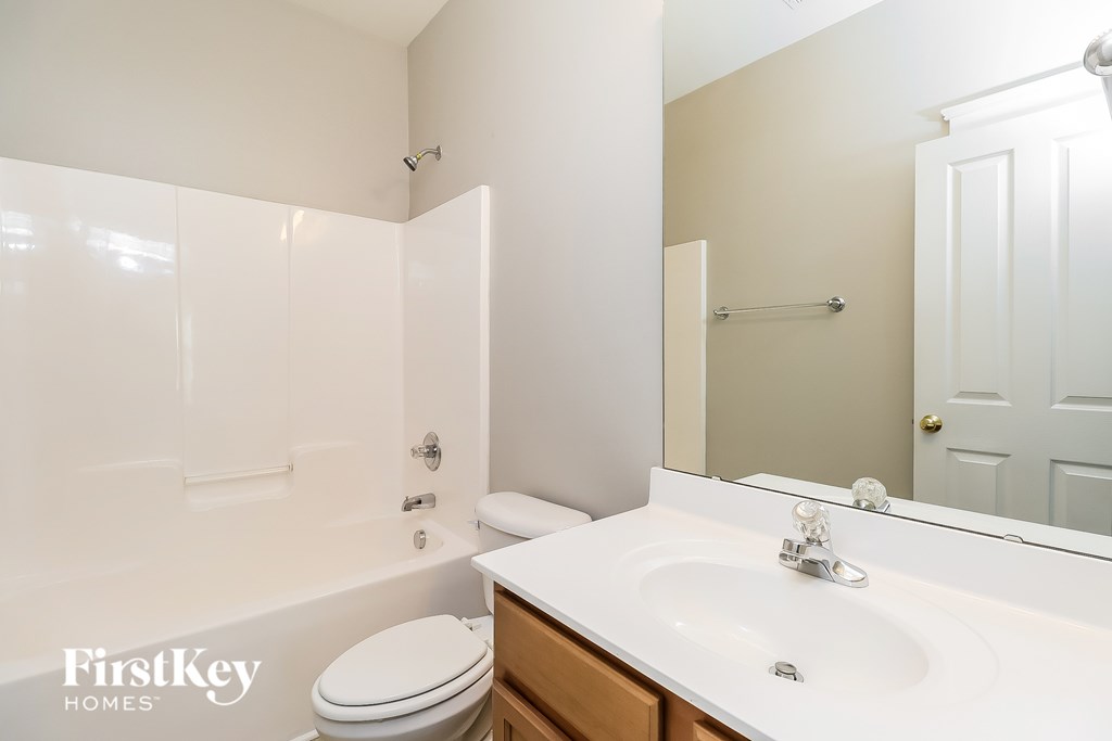 A white bathroom with a toilet, sink and mirror.