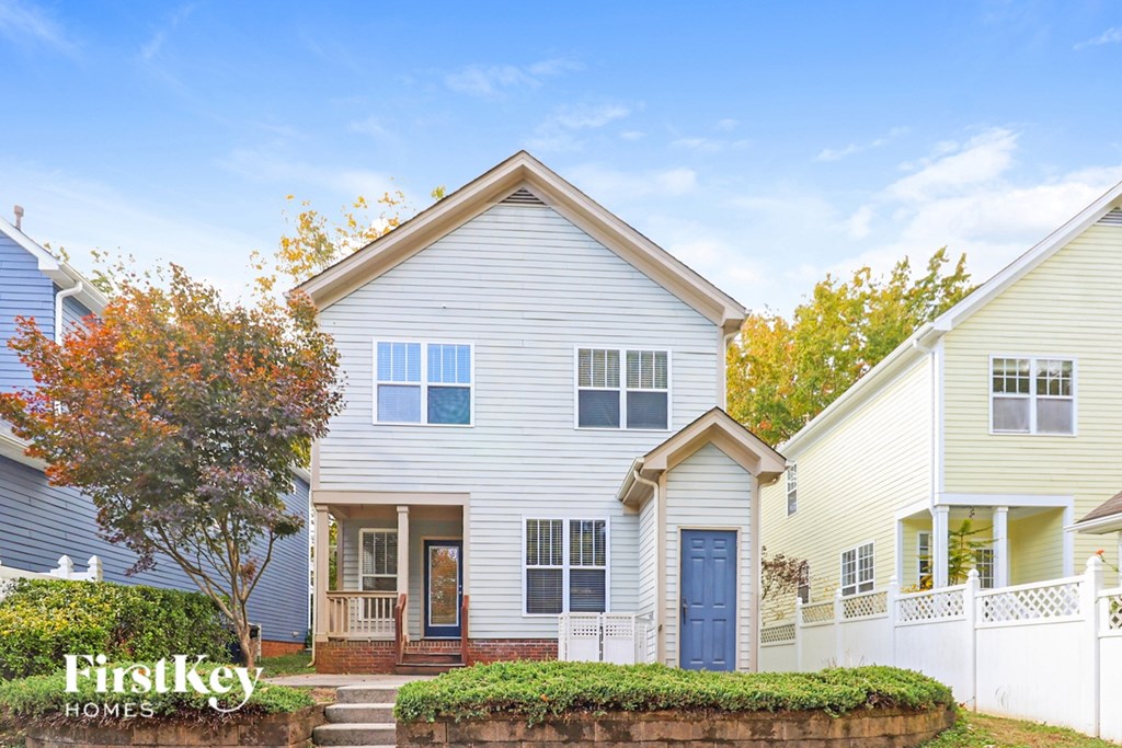 A house with a blue door and a white fence in front of it.