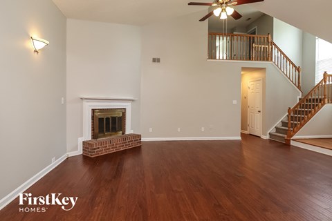 A spacious living room with a fireplace and a staircase.