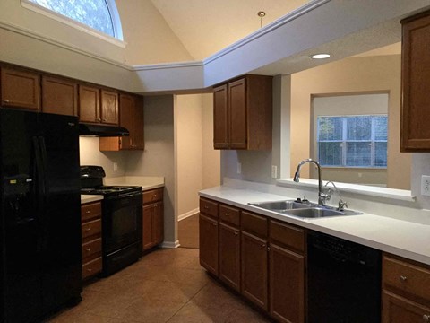 A kitchen with black appliances and brown cabinets.