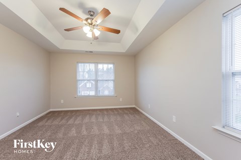 the spacious living room with ceiling fan and carpet