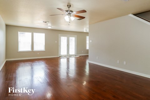 A spacious room with wood flooring and a ceiling fan.