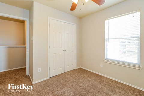 A bedroom with a white door and a window with blinds.