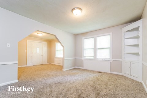 A carpeted room with a doorway leading to another room.