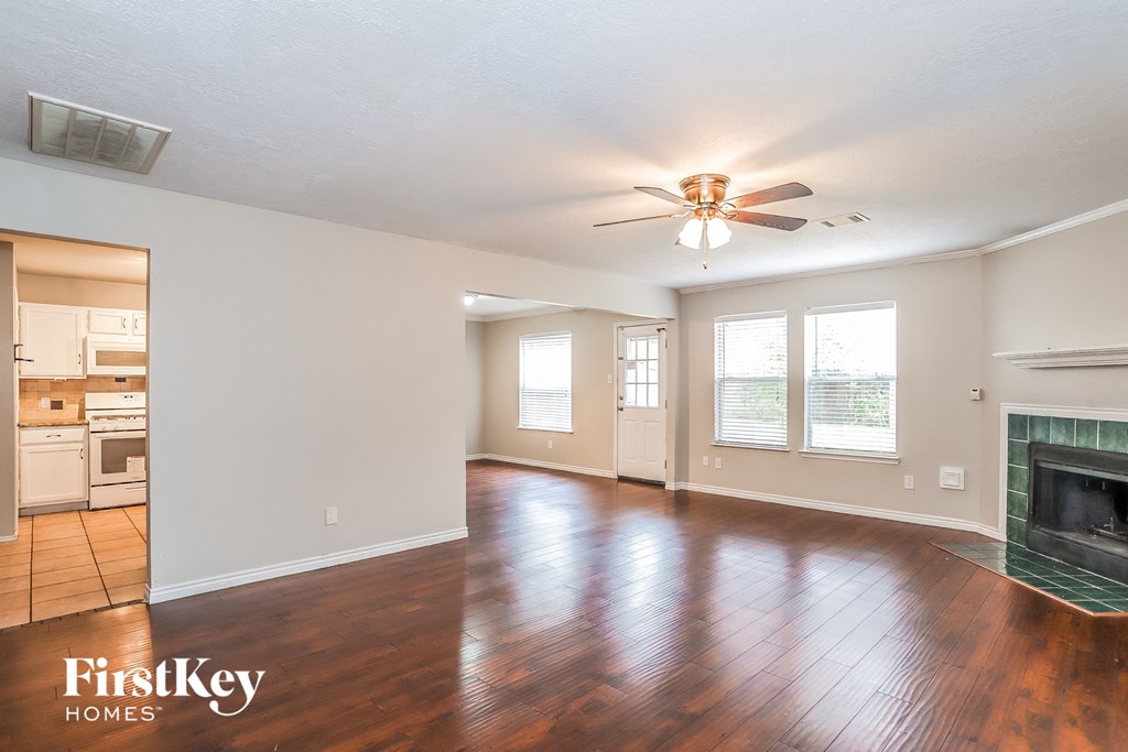 A spacious living room with wood flooring and a fireplace.