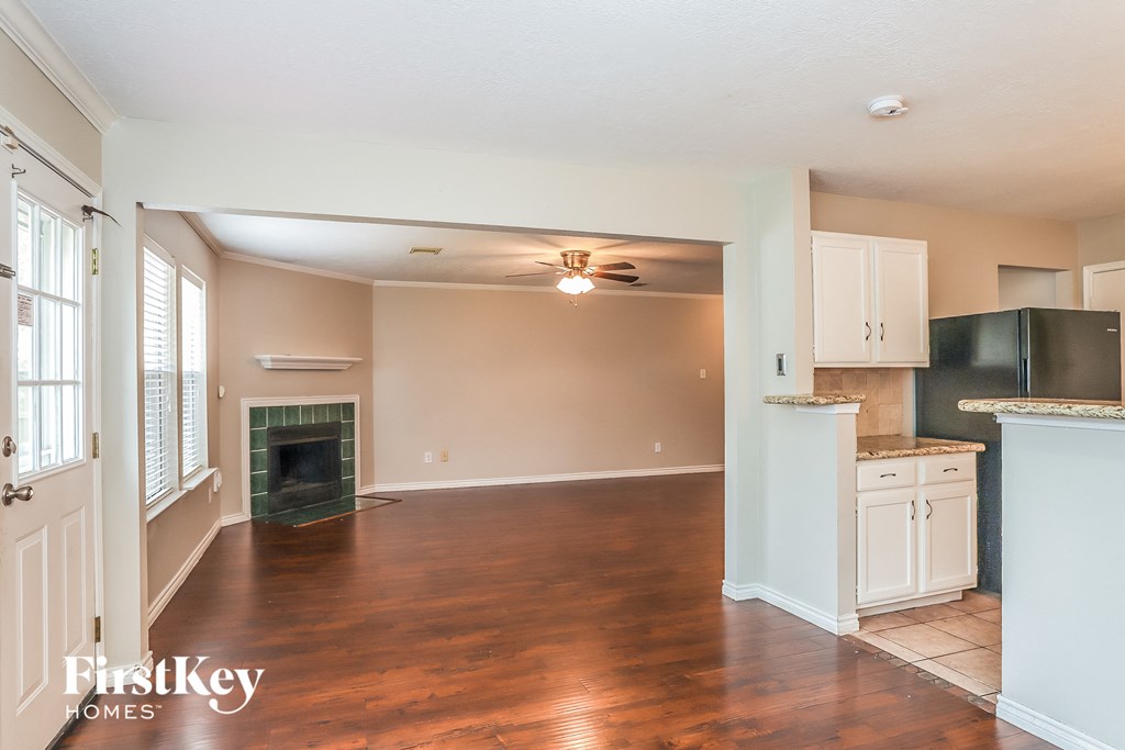 A spacious living room with a fireplace and a kitchen area in the background.