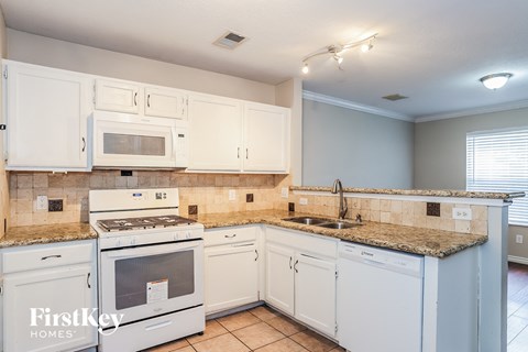 A kitchen with white cabinets and appliances.