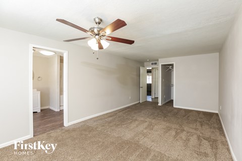 a living room with a ceiling fan and a carpet