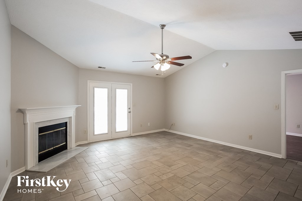 A spacious room with a fireplace and a ceiling fan.