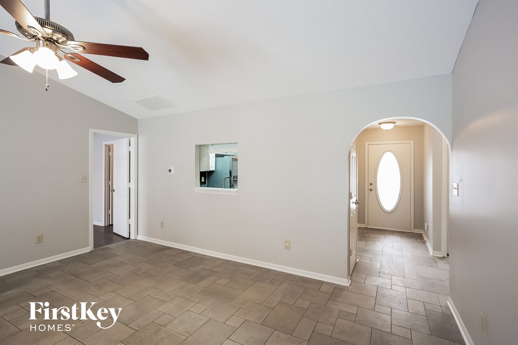 A spacious room with a ceiling fan and tiled flooring.